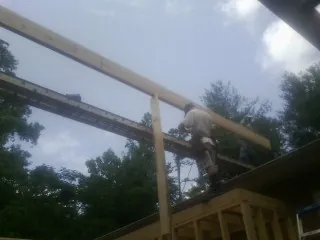 Carpenter setting a ridge beam over a new addition frame — Ice Dam Removal by Roofing Brothers in Farmersburg