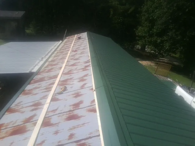 Old rusted panels beside newly installed green metal roofing — Wind Damage Roof Repair by Roofing Brothers in Farmersburg
