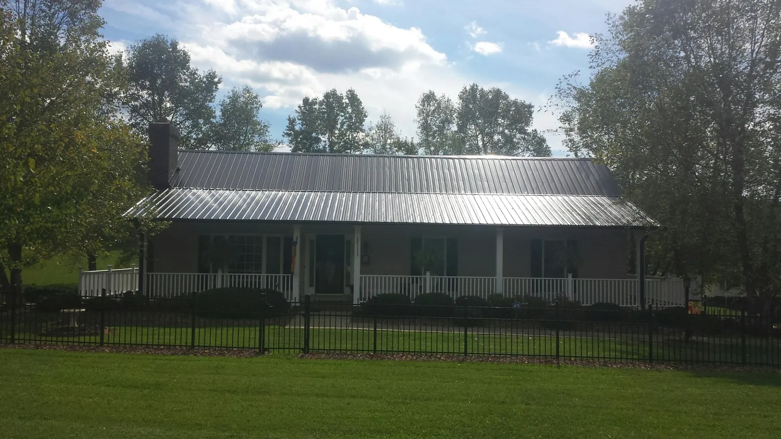 Gray metal roof on a brick ranch with a full width front porch — Gutter Guard Installation work by our crew in Farmersburg