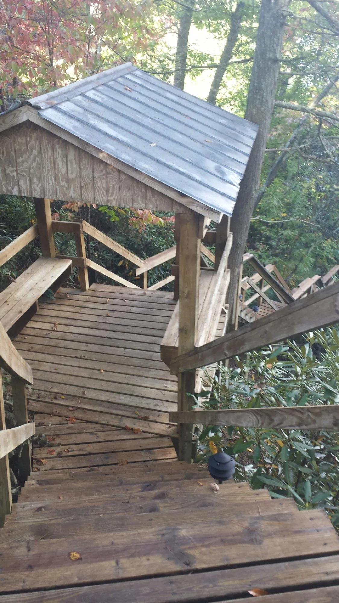 Metal roofed shelter over wooden steps on a wooded walkway — Skylight Repair & Installation work by our crew in Farmersburg