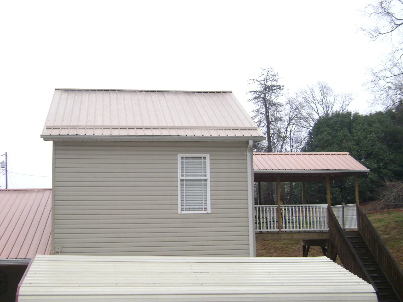 Tan metal roofs on a two story addition and attached porch, from a Roof Replacement job in Farmersburg