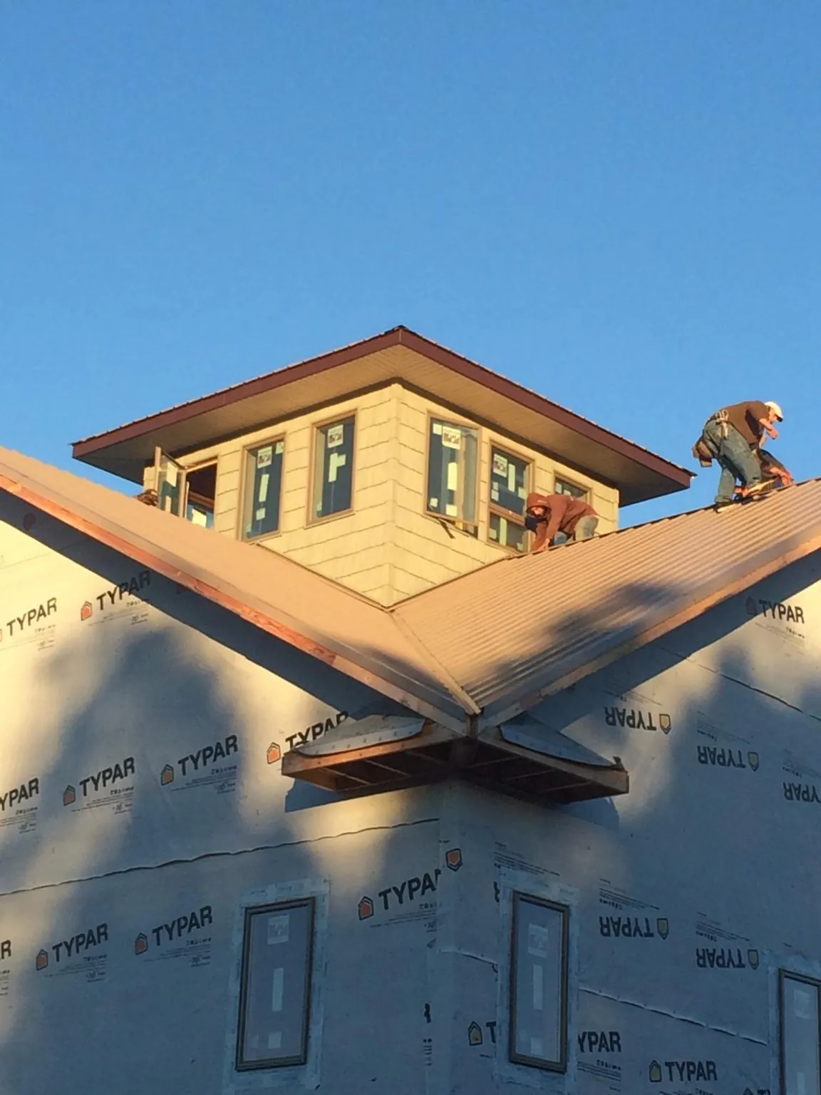 Roofers working around a rooftop cupola on a new metal roof at sunset — Roof Waterproofing in Farmersburg by Roofing Brothers